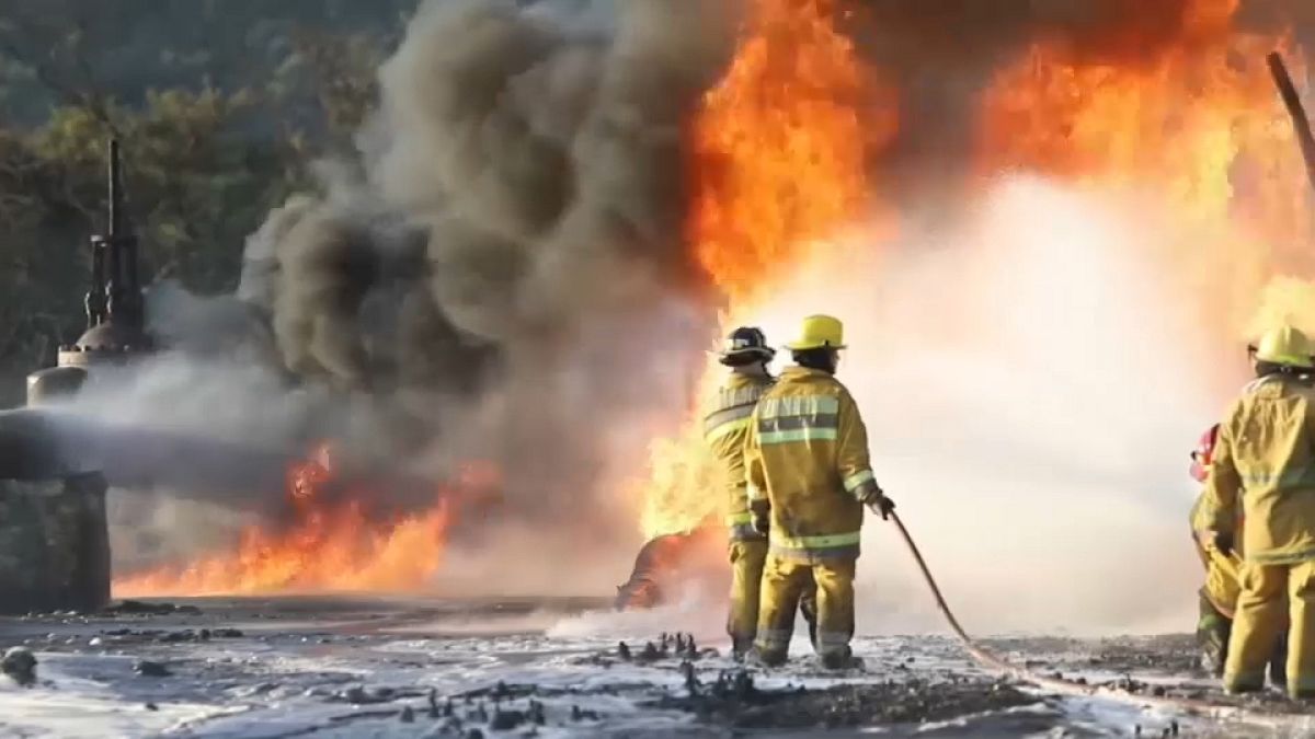 Los bomberos trabajando para contener las llamas tras la explosión en un ducto de gasolina en Venezuela.