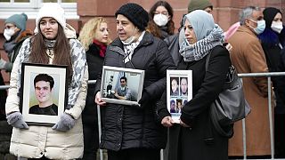 Suriyeli kadınlar Koblenz'deki mahkeme önünde karar öncesi Suriye'de ölen akrabalarının fotoğraflarını tutuyor