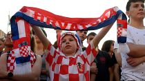 A young supporter holds a scarf as people watch a broadcast of the UEFA EURO 2020 football match between Croatia and Czech Republic at the Jelacic square in Zagreb