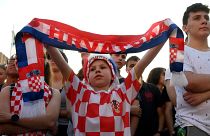A young supporter holds a scarf as people watch a broadcast of the UEFA EURO 2020 football match between Croatia and Czech Republic at the Jelacic square in Zagreb