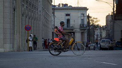 Un uomo e un bambino, indossando maschere protettive, passano in bicicletta all'Avana, Cuba, giovedì 30 dicembre 2021