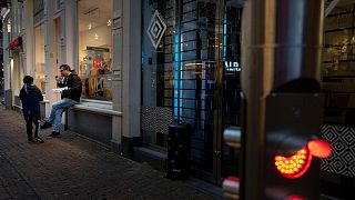 FILE- Closed restaurants because of a lockdown forced people to eat outdoors next to a closed shop in Amsterdam, Netherlands.