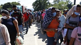 Migranten stehen Schlange und darauf, dass ihre Dokumente von der Polizei in Corinto, Honduras, überprüft werden (15. Januar 2022).