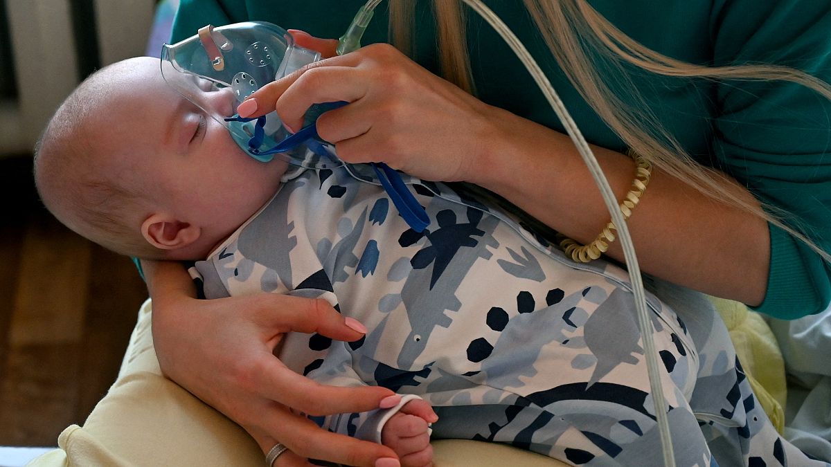 امرأة تحمل قناع أكسجين على وجه طفلها المصاب بفيروس كورونا (كوفيد -19) في جناح بمستشفى للأطفال في كييف. 2021/11/16