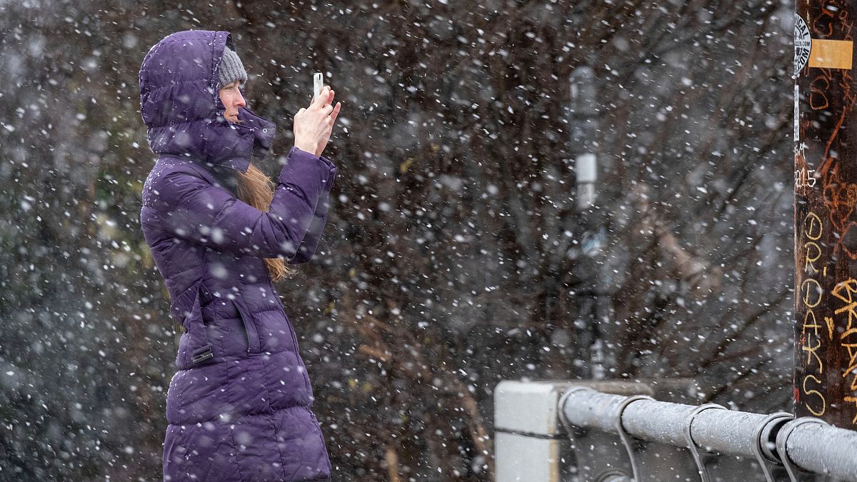 امرأة تلتقط صورة للثلج أثناء تساقط الثلوج في أتلانتا بينما تضرب عاصفة شتوية المنطقة. 2022/01/16