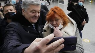 Former Ukrainian President Petro Poroshenko, left, poses for a selfie with a Ukrainian supporter at Warsaw's international airport before boarding a flight to Kyiv, Ukraine