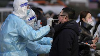 رجل يحصل على مسحة من الحلق لاختبار كوفيدـ19 في منشأة متنقلة لاختبار فيروس كورونا خارج مباني المكاتب التجارية في بكين. 2022/01/17