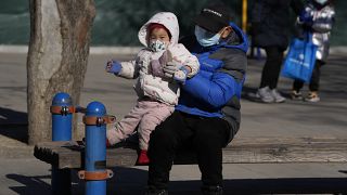 A man lifts a child at a park in Beijing, China, Thursday, Jan. 13, 2022.