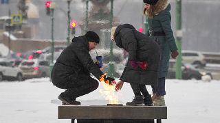 People warm themselves up near the eternal flame at the Mars Field in St.Petersburg, Russia, Friday, Jan. 15, 2021. The temperature in St. Petersburg is -15C