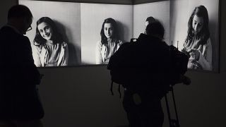 FILE- Journalist takes images of pictures of Anne Frank at the renovated Anne Frank House Museum in Amsterdam, Netherlands, Wednesday, Nov. 21, 2018.