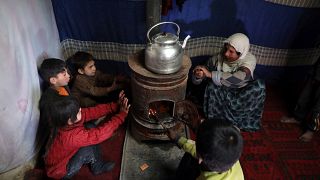 أطفال نازحون يجلسون حول موقد للتدفئة في ملجأ مؤقت في مدينة كابل، أفغانستان2020/12/30
