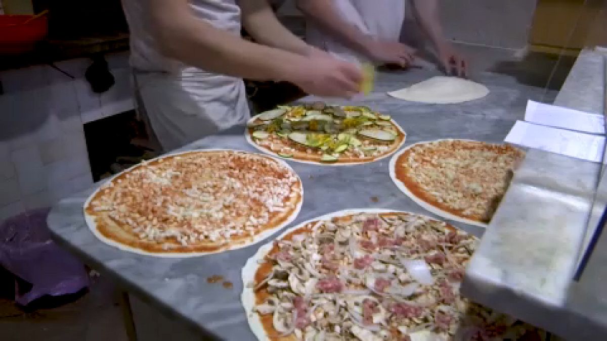 طهاة في أحد المطاعم بالعاصمة روما يعدّون الـ"بيتزا" الإيطالية لزبائنهم 17 يناير 2022