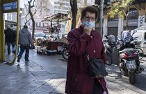 امرأة مسنة ترتدي كمامة للحد من انتشار فيروس كورونا تمشي في وسط أثينا. 2022/01/17
