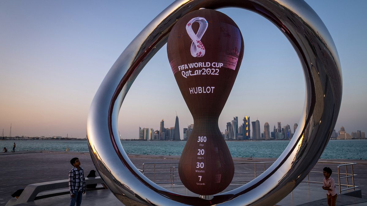 أطفال بالقرب من ساعة العد العكسي الرسمية لمونديال قطر 2022 في الدوحة 