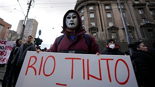 A protester wearing a mask holds a banner during a protest in front of the government building in Belgrade, Serbia, Saturday, Dec. 18, 2021.