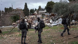 قوات إسرائيلية إلى جانب منزل دمرته في حي الشيخ جراح في القدس الشرقية