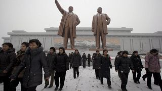 كوريون يحتشدون أمام تماثيل كيم إيل سونج وكيم جونغ إيل في نصب مانسو هيل الكبير في بيونغيانغ