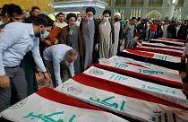 Mourners pray over the flag-draped coffins of civilians killed in an attack by the Islamic State extremist group in the village of al-Rashad, Oct. 27, 2021.