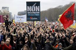 Protestors clap as they gather with signs and banners during a demonstration against COVID-19 measures in Brussels, Sunday, Jan. 23, 2022.