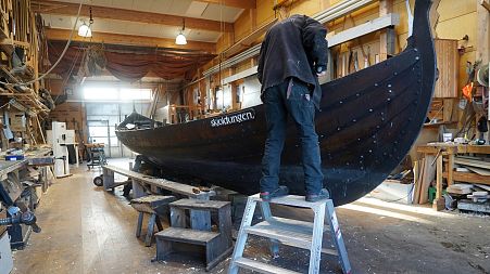 A man repairs one of the Nordic region's traditional Viking-era clinker boats