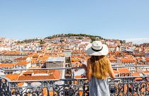A woman looks out across the rooftops of Lisbon