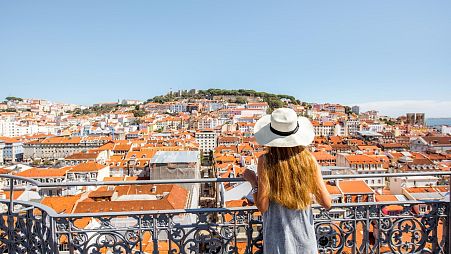 A woman looks out across the rooftops of Lisbon