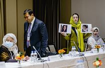 Heda Khamoush, a delegate from Afghan civil society to talks with Western diplomats, holds up photos of two women who have vanished on Monday