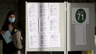 A young woman leaves a voting booth at a polling station for early voters in Portugal's general election, at the University of Lisbon, Sunday, Jan. 23, 2022