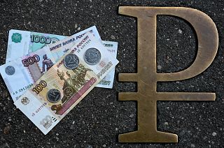 This picture taken on August 13, 2021, in Moscow, shows Russian ruble coins and banknotes pictured next to Russian ruble sign.