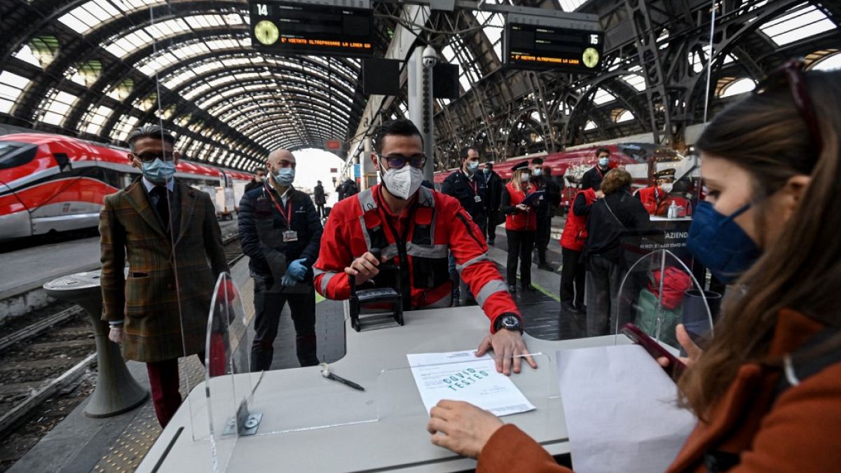 An employee validates coronavirus test certificate to passengers on a platform of a train station in Milan.