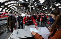 An employee validates coronavirus test certificate to passengers on a platform of a train station in Milan 