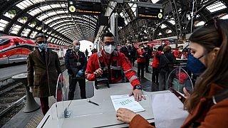 An employee validates coronavirus test certificate to passengers on a platform of a train station in Milan.