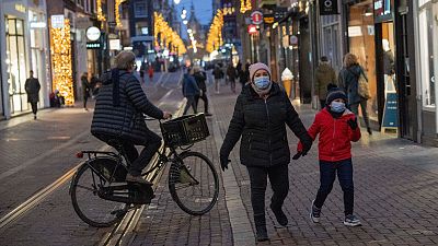 People walk in one of the capital's main shopping streets during a lockdown in Amsterdam, Netherlands, Thursday, Dec. 30, 2021.
