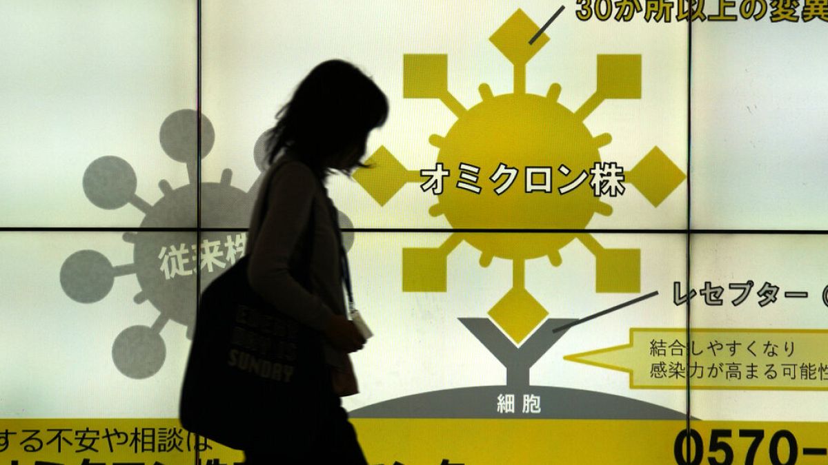 Japán nő sétál el a Tokió egyik aluljárójában elhelyezett, a koronavírusról szóló ismertetők előtt