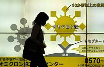 Japán nő sétál el a Tokió egyik aluljárójában elhelyezett, a koronavírusról szóló ismertetők előtt