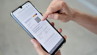 A woman checks her EU Digital Covid certificate on her mobile phone at El Prat airport in Barcelona.