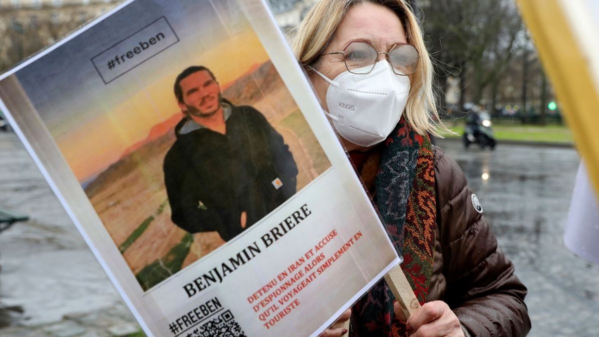 A woman holds a photo of Benjamin Briere during a rally in Paris earlier this month.