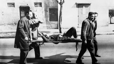 متطوعون يحملون جثة أحد ضحايا إطلاق النار في شارع إيسلي بالجزائر العاصمة في 26 مارس 1962