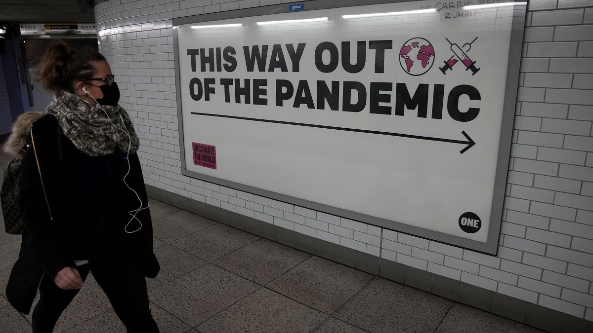 Une femme passe devant l'affiche de campagne de l'ONG One à Londres, affiche qui dit "par ici pour la sortie de la pandémie", le 27 janvier 2022