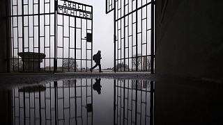 A person walks behind the gate of the Sachsenhausen Nazi death camp with the phrase 'Arbeit macht frei' in Oranienburg, Berlin