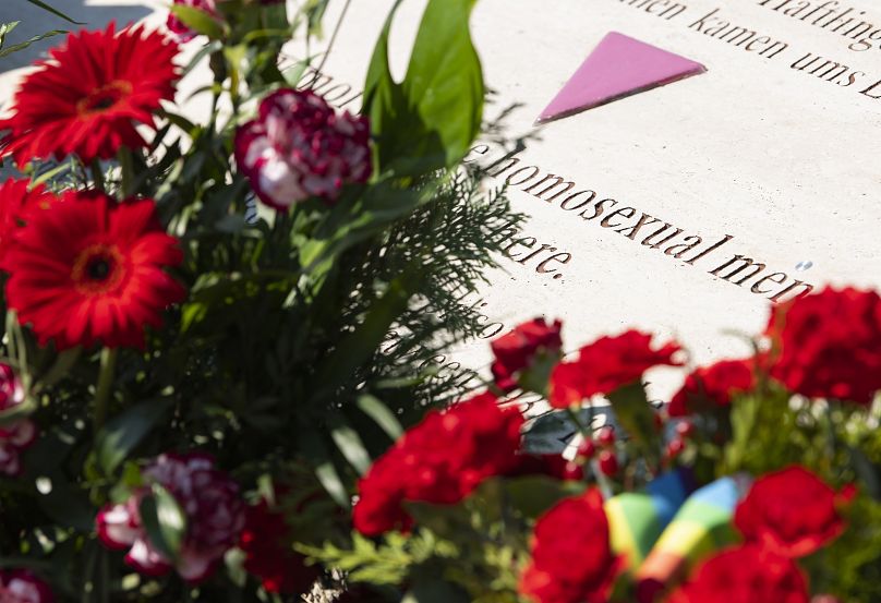 Flowers are placed at a memorial stone in remembrance for prisoners assigned a pink triangle in the former Nazi concentration camp Buchenwald in 2019 - AP Photo/Jens Meyer