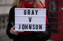 An anti-Boris Johnson protester holds a placard as a reference to the Sue Gray report, on the junction of Parliament Street and Parliament Square, in London, Jan. 26, 2022.