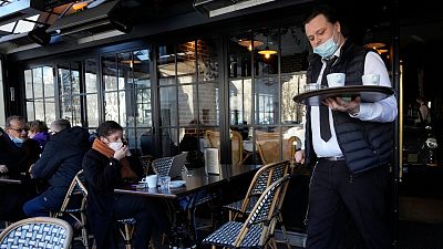 A waiter serves coffee in a restaurant, in Paris on 24 January 2022. 