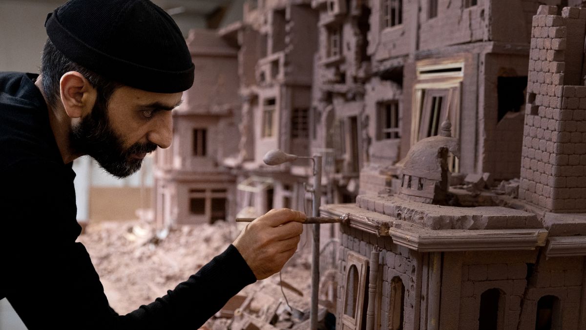 Syrian sculptor Khaled Dawwa works on a clay artpiece, representing a street in Syria destroyed by Syrian regime forces, in his workshop in Vanves, near Paris, January 9, 2022
