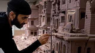 Syrian sculptor Khaled Dawwa works on a clay artpiece, representing a street in Syria destroyed by Syrian regime forces, in his workshop in Vanves, near Paris, January 9, 2022