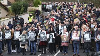 People take part in a march to commemorate the 50th anniversary of the 'Bloody Sunday' shootings with the photographs of some of the victims in Londonderry, Sunday