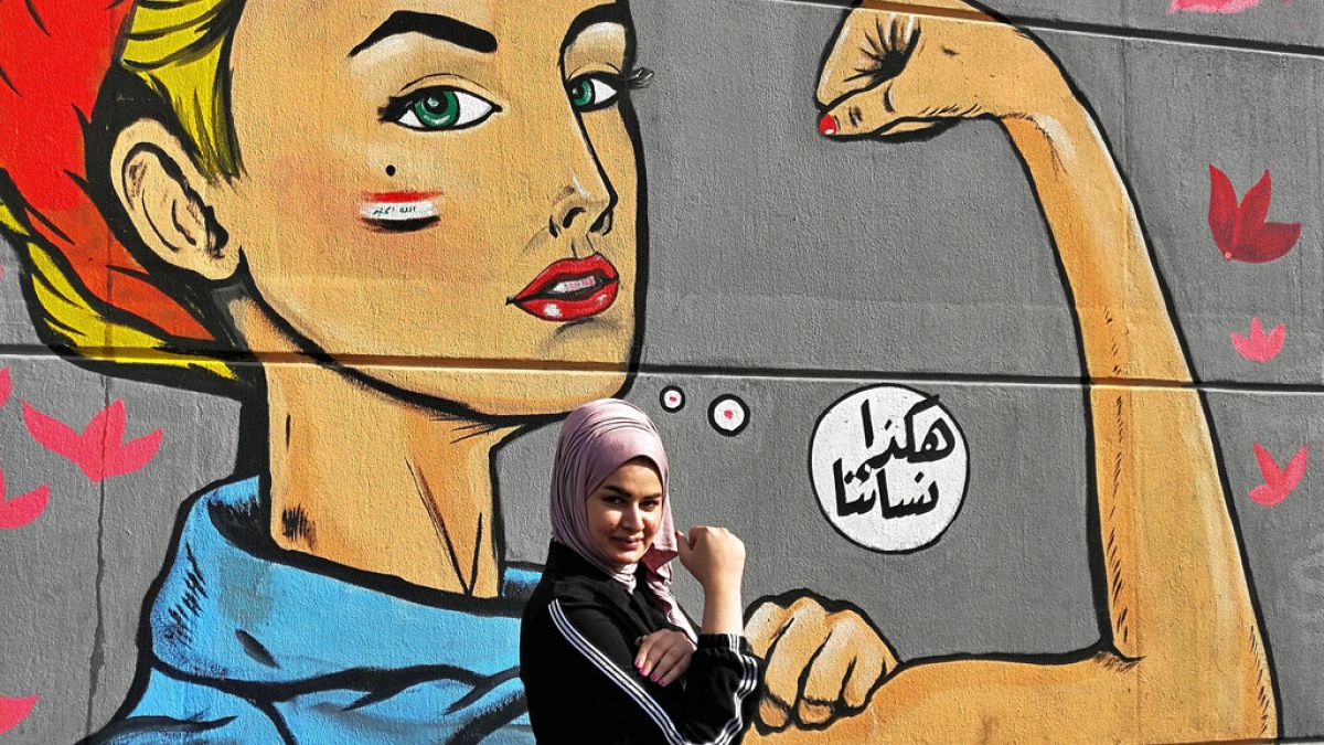 امرأة تقف لالتقاط صورة بالقرب من غرافيتي كتب عليه بالعربية "هكذا نسائنا"، بالقرب من ساحة التحرير في بغداد، العراق، الخميس 7 نوفمبر 2019