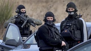 Police officers prepare for an operation close to a road where two police officers were shot during a traffic stop near Kusel, Germany
