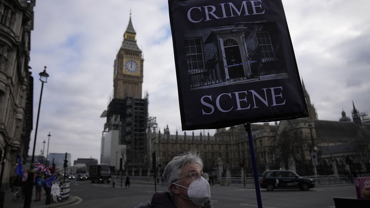 Un manifestante sostiene una pancarta con el telón de fondo de la Torre Elizabeth y las Casas del Parlamento, en Londres, el 26 de enero de 2022.