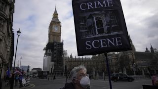 Un manifestante sostiene una pancarta con el telón de fondo de la Torre Elizabeth y las Casas del Parlamento, en Londres, el 26 de enero de 2022.